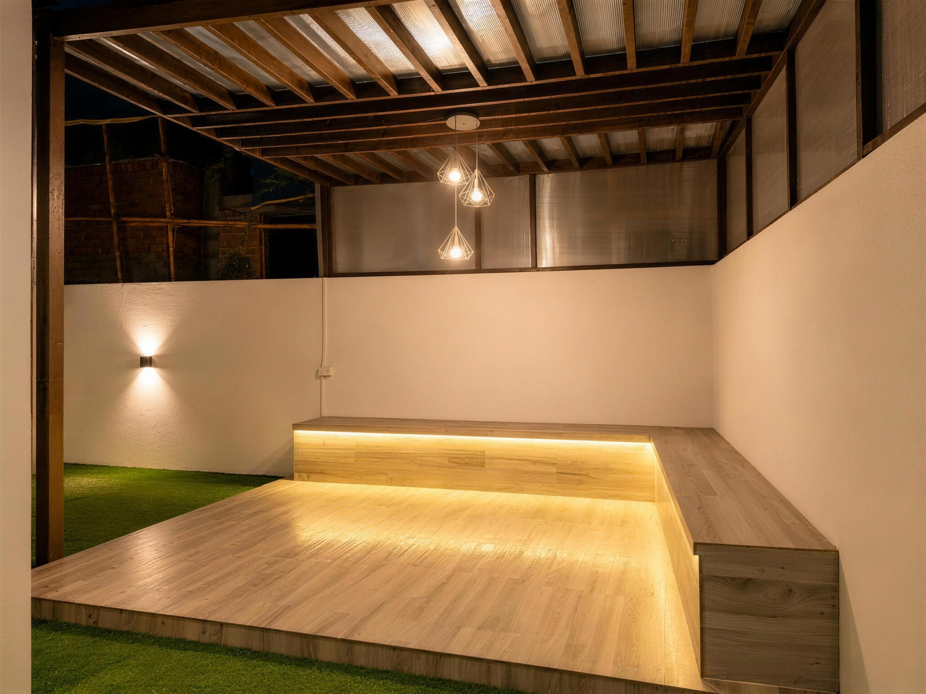 The same roof deck in warm evening light, the bench's strip light and the pendant lamps glowing, the frame squared and cleared.